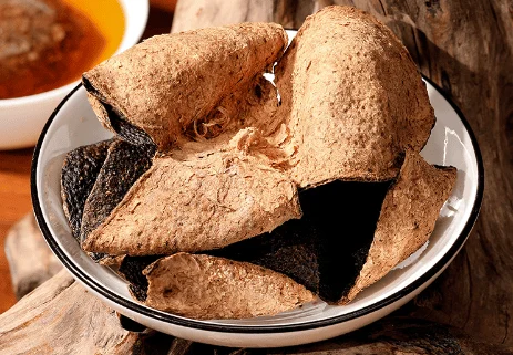Aged Xinhui Chenpi (dried tangerine peel) displayed in a white porcelain bowl, showing its golden outer skin and dark inner surface — a hallmark of well-matured Chenpi.