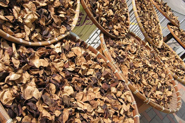 Traditional sun-drying method for Xinhui Chenpi citrus peel in bamboo trays, exposed to natural sunlight in Guangdong, China.