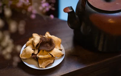 A moody, aesthetic shot of premium Xinhui Chenpi ready for brewing, presented next to a rustic cast iron teapot, evoking the tranquility of a traditional Chinese tea ceremony.